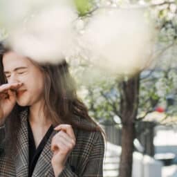 Woman scratches nose in a park