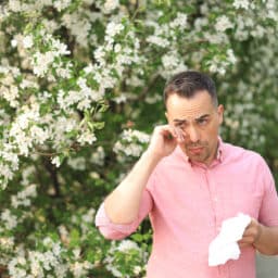 Man with allergies rubbing his eyes.