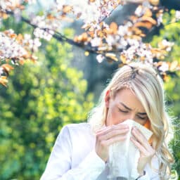 Woman sneezing under a tree