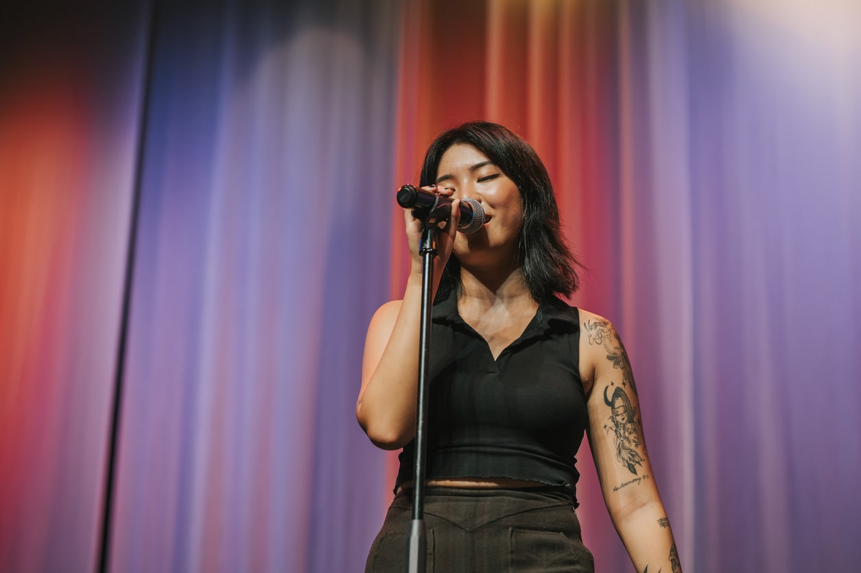 Woman singing on a colorful stage.