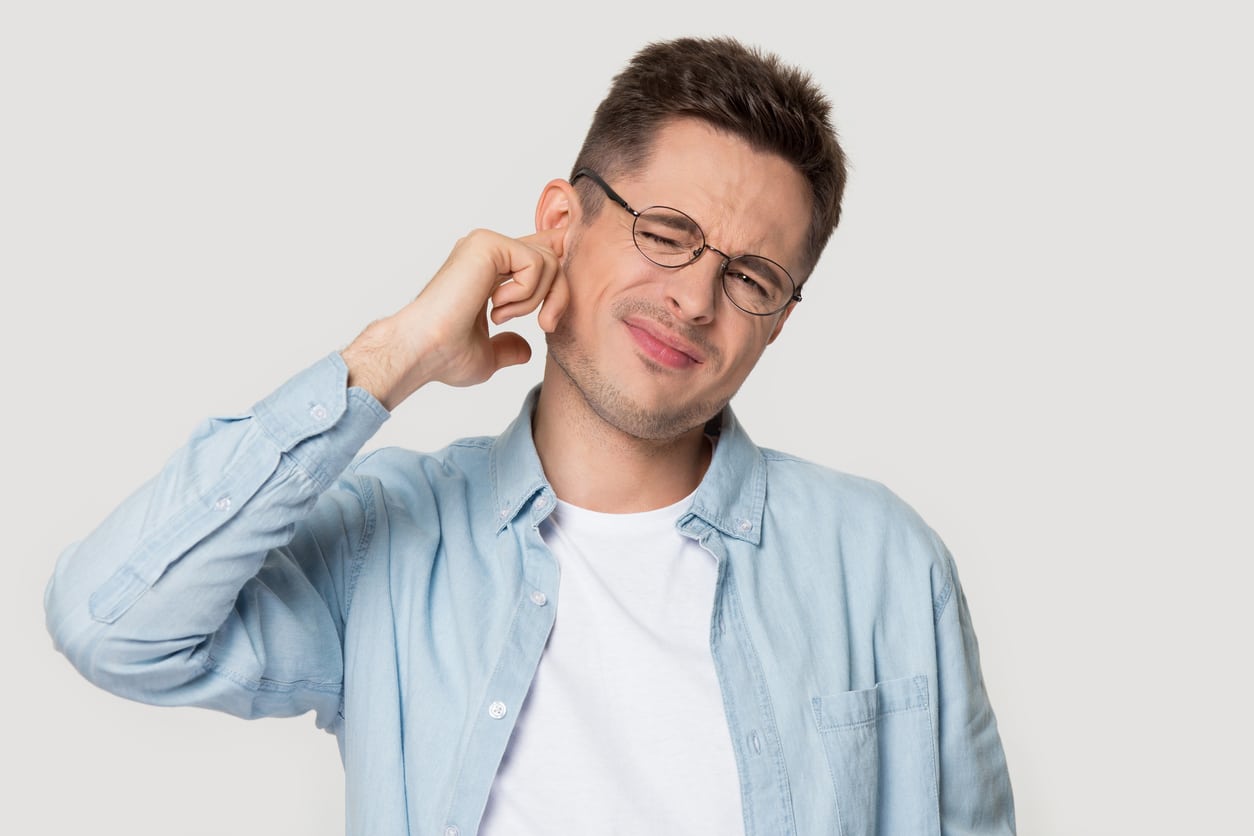 Man with ear irritation holds ear