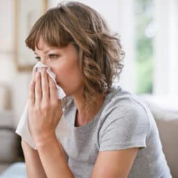 Woman blowing her nose into a tissue