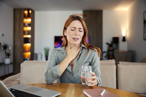 Woman feeling discomfort from a sore throat.