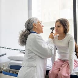 Doctor examining a young girl's ear.