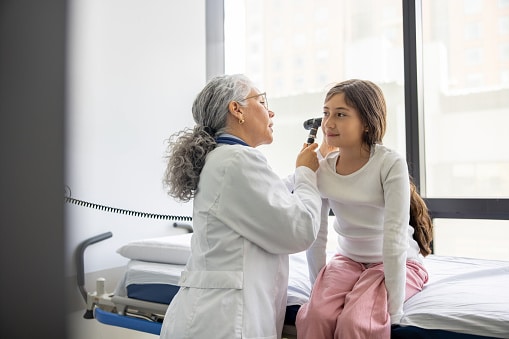Doctor examining a young girl's ear.