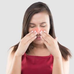 Woman touching her red sinuses.